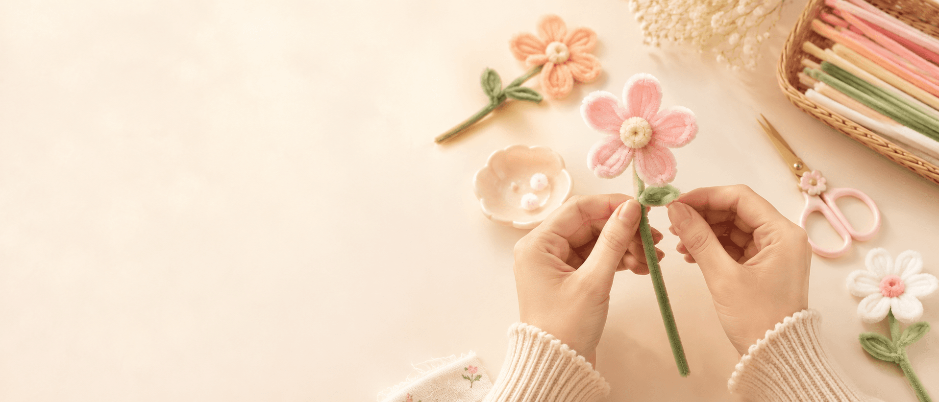 Hands making a pink pipe cleaner flower with craft supplies